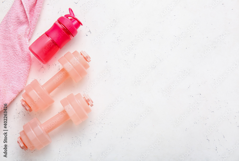 Stylish dumbbells, bottle of water and towel on light background Stylish dumbbells, bottle of water and towel on light background