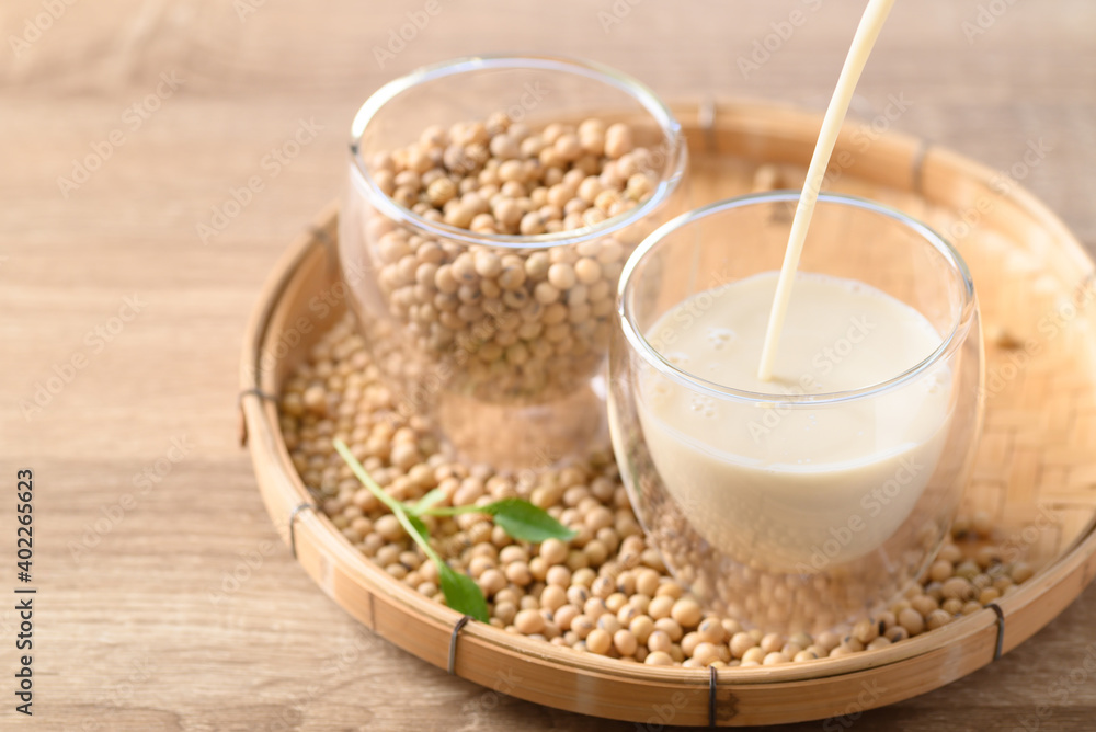 Soy milk pouring into a glass with soybeans on bamboo tray, Healthy drink Soy milk pouring into a glass with soybeans on bamboo tray, Healthy drink
