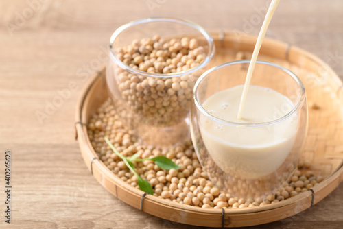 Soy milk pouring into a glass with soybeans on bamboo tray, Healthy drink