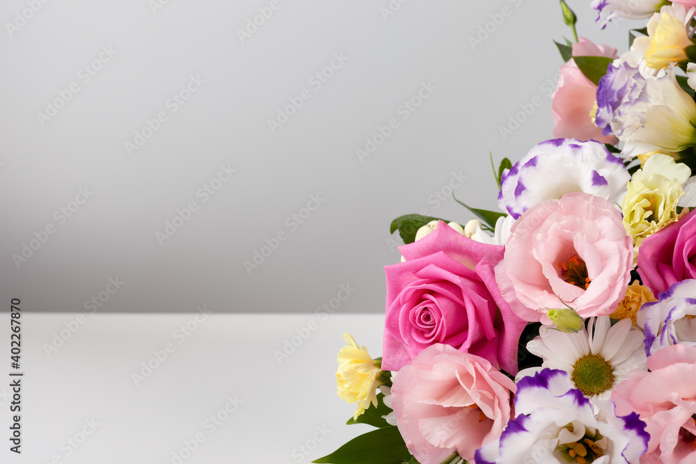 mock up bouquet of roses, daisies, lisianthus, chrysanthemums, unopened buds on a white table and wall.