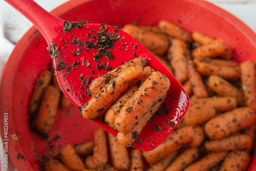 Red spoon with small peeled pieces of cooked carrot photo