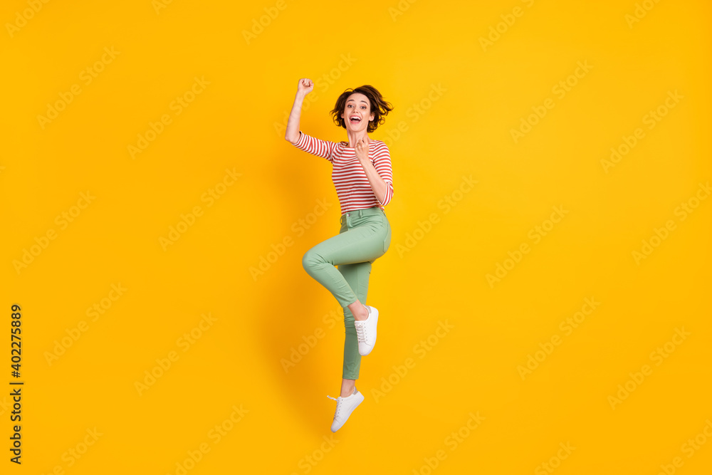Full length body size view of charming cheerful girl jumping rejoicing having fun isolated over bright yellow color background Full length body size view of charming cheerful girl jumping rejoicing having fun isolated over bright yellow color background