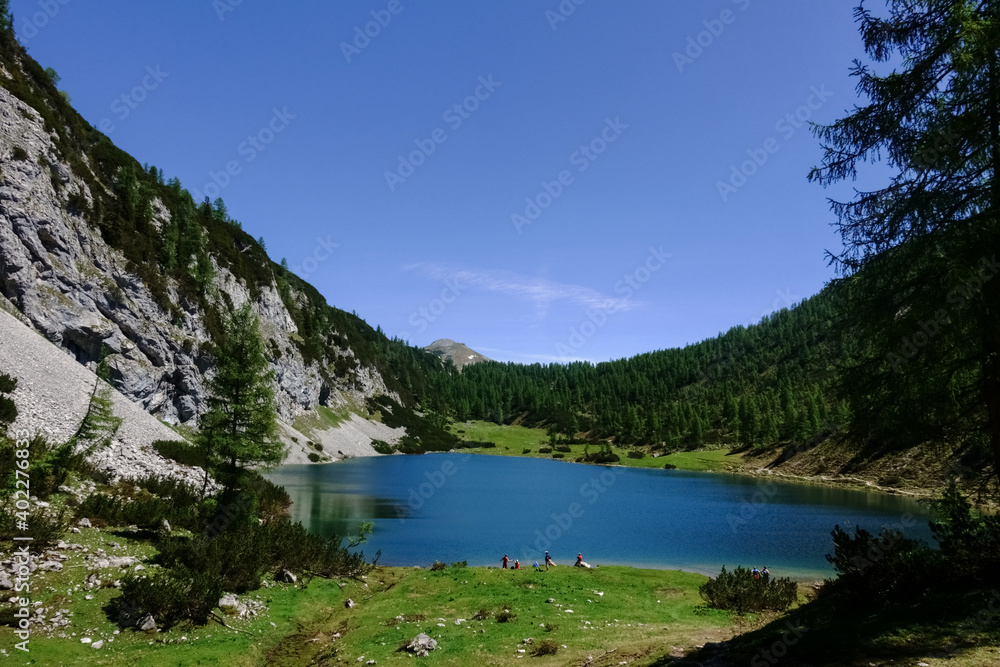 hikers on a blue mountain lake with blue sky in the summer