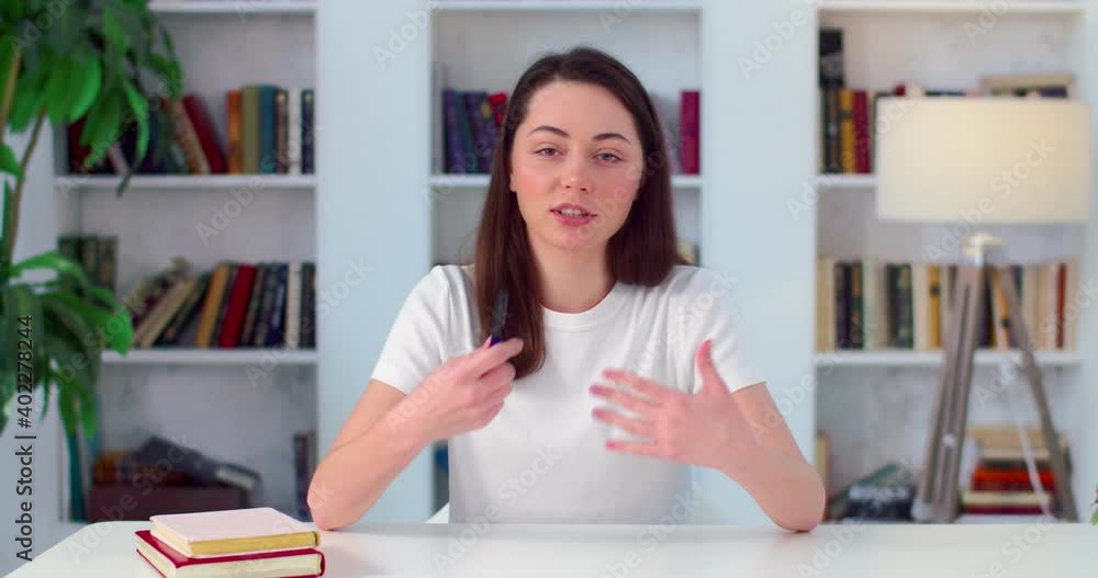 Caucasian young woman virtual teacher consulting patient teaching student looking talking to camera make conference call recording video training sit on sofa at home office, webcam view Caucasian young woman virtual teacher consulting patient teaching student looking talking to camera make conference call recording video training sit on sofa at home office, webcam view