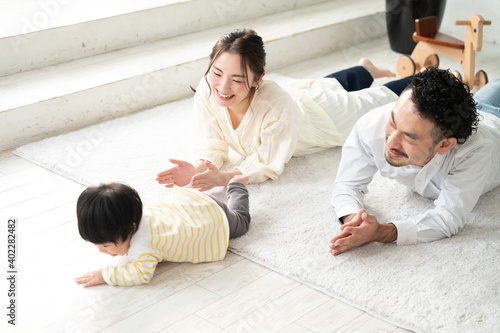 ハイハイをはじめる赤ちゃんを応援する幸せなママとパパの家族