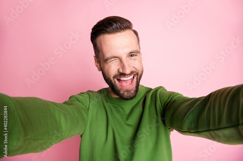 Self-portrait of nice cheerful mature funky guy having fun winking isolated over pink pastel color background © deagreez