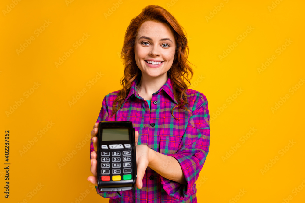 Portrait of charming lady giving you terminal to pay wear checkered purple isolated on yellow color background Portrait of charming lady giving you terminal to pay wear checkered purple isolated on yellow color background