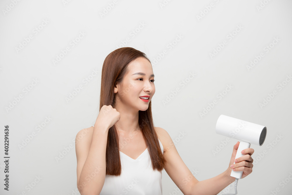 Asian woman uses hair dryer on white background. Asian woman uses hair dryer on white background.