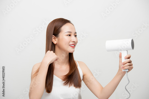 Beautiful Asian girl drying her hair with hairdryer.