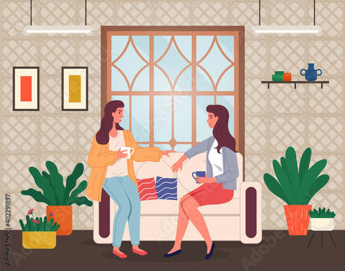 Brunette women sitting at sofa and talking. Friends relaxing at home with a cup of tea or coffee. Happy spending leisure time at home. Sisters talking, relaxing at couch near window in living room