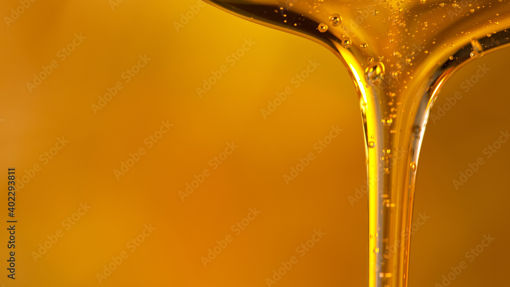 Pouring oil or honey drop on golden background. Macro shot. - obrazy, fototapety, plakaty 