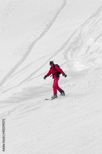 Snowboarder downhill on snowy off-piste slope after snowfall