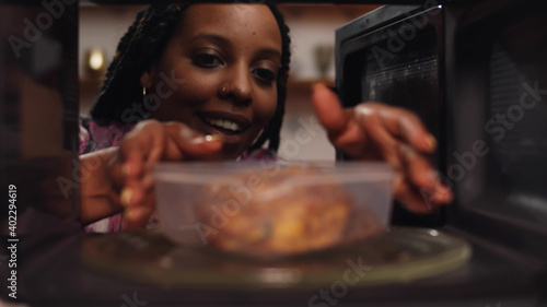 Afro-american woman using the microwave oven to heating food. photo