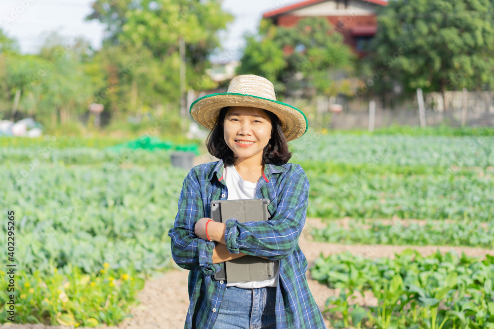 close up on asian farmer woman holding digital tablet at the organic vegetable farm to check and control quality of product to market for agricultural and technology concept