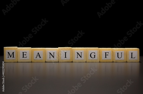 The word MEANINGFUL written on wooden cubes isolated on a black background