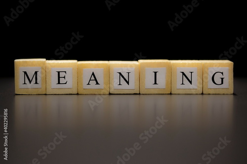 The word MEANING written on wooden cubes isolated on a black background photo