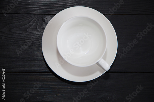 White porcelain cup empty with saucer on dark wooden background.