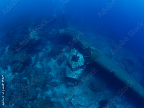 scuba divers exploring airplane wreck underwater taking photos of c47 dakota airplane engine 