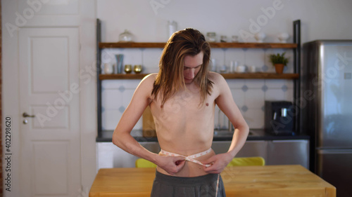 Canvastavla Young thin shirtless man measuring waist with tape at home