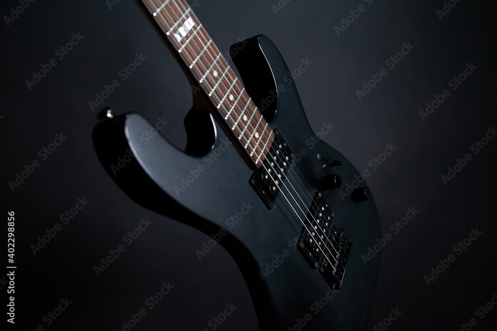 Fototapeta premium Black electric guitar on a dark background with backlit strings