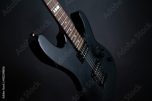 Black electric guitar on a dark background with backlit strings