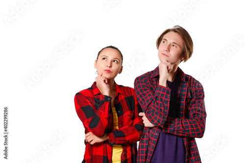 a guy and a girl in casual clothes, checkered shirts are standing and looking thoughtfully towards the copyspace