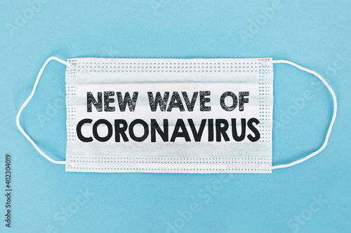 Medical face mask with NEW WAVE OF CORONAVIRUS text on blue background.