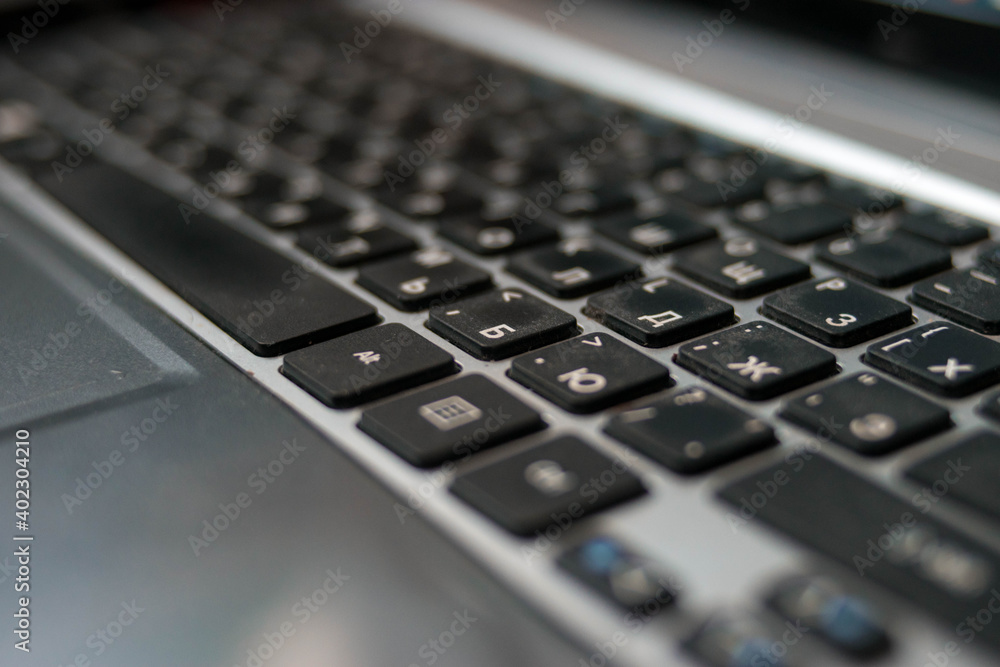 Laptop keyboard. White letters and black keys. Gray computer. Digital technologies