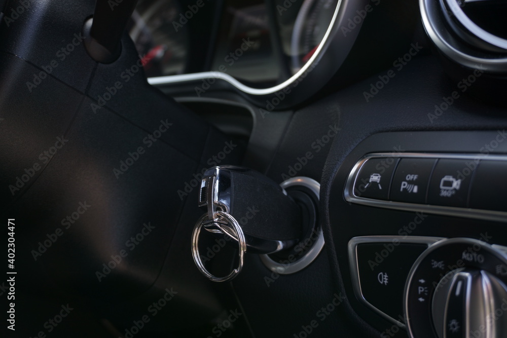 Electronic key in ignition of modern luxury car. Lights and driver assists panel in foreground.