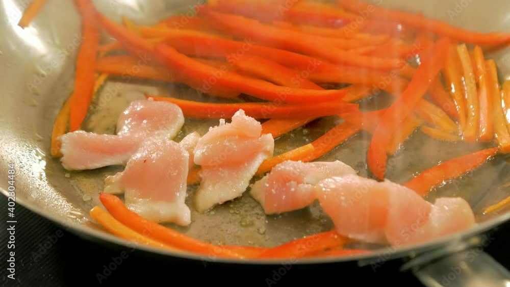 Sprinkling salt over fried vegetables and chicken in a steel pan, handheld close up shot Sprinkling salt over fried vegetables and chicken in a steel pan, handheld close up shot