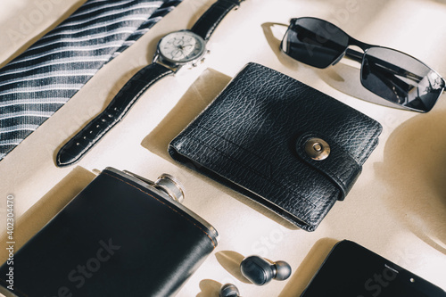 Top view male object, watch, flask, tie, belt, cell phone, wallet, notebook, headphones.