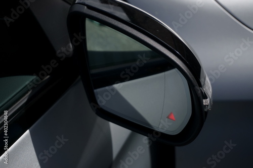 Car door mirror with illuminated blind spot monitoring light warning.
