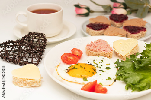 Romantic breakfast for Valentine s Day. Fried eggs in the shape of a heart  bread with jam and flower tea.