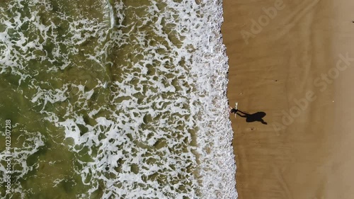 a surfer walking along the beach