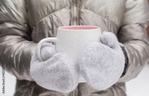 Winter girl in gloves holds a mug on a cold winter day. Place for inscription