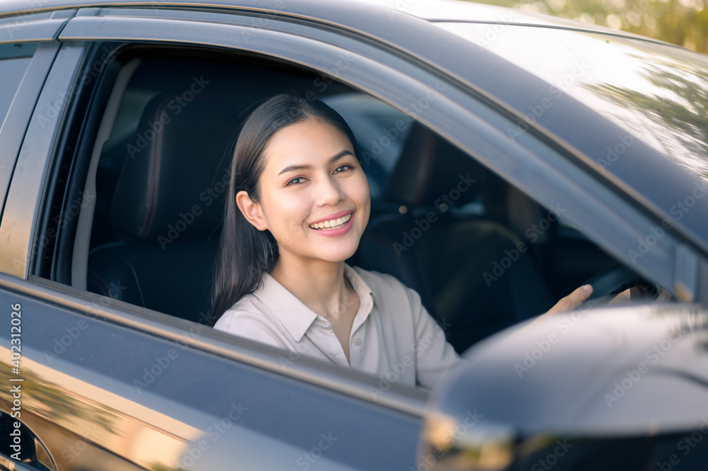 Beautiful young smiling woman driving her car, insurance and finance concept