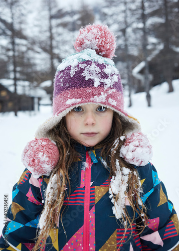Bambina primo piano con cappello nella neve in montagna photo