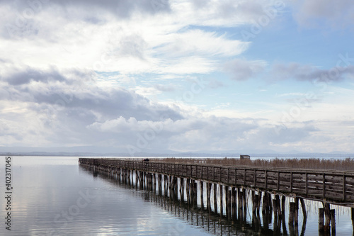 Panorama of a wooden Pier on Trasimeno lake in a cloudy day,  "La valle"  San Savino,  naturalistic oasis landscape  in the municipality of Magione,  Umbria, Italy. © Francesca