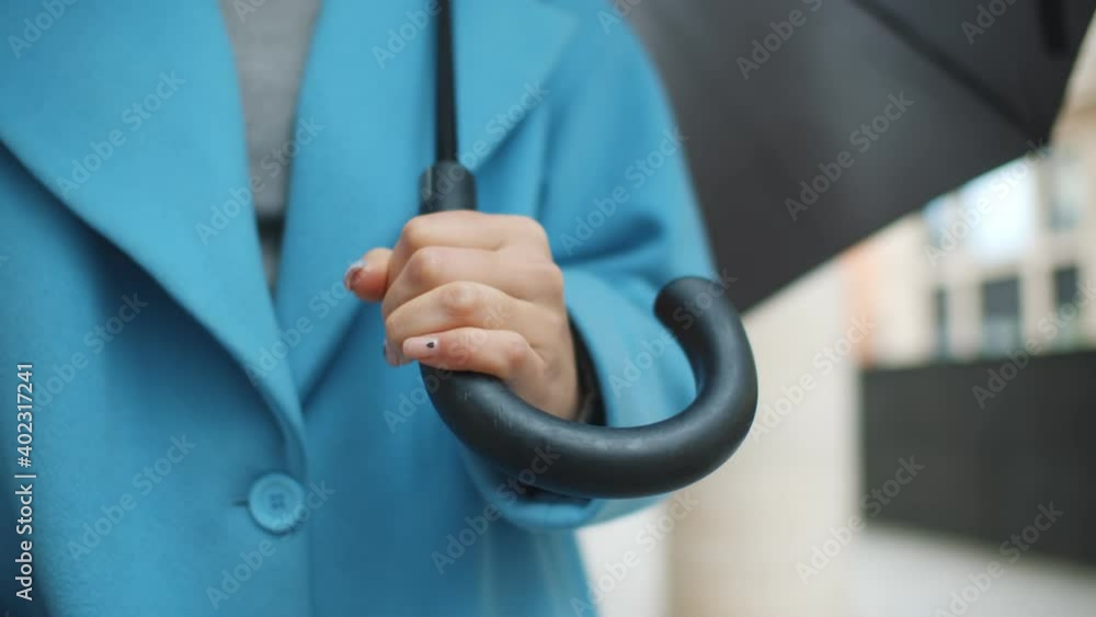 Close up of woman in blue coat holding umbrella in manicured hand outdoors Close up of woman in blue coat holding umbrella in manicured hand outdoors