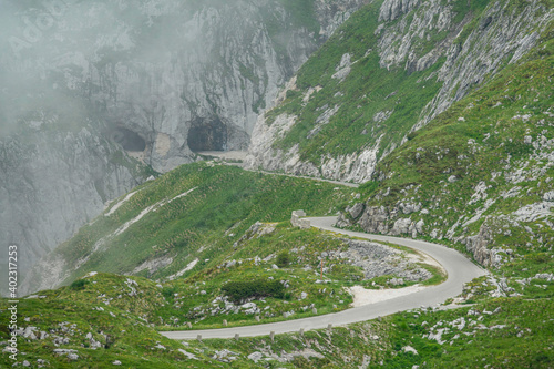 Mist rolls down along the grassy hills and empty road of a mountain in the Alps. photo