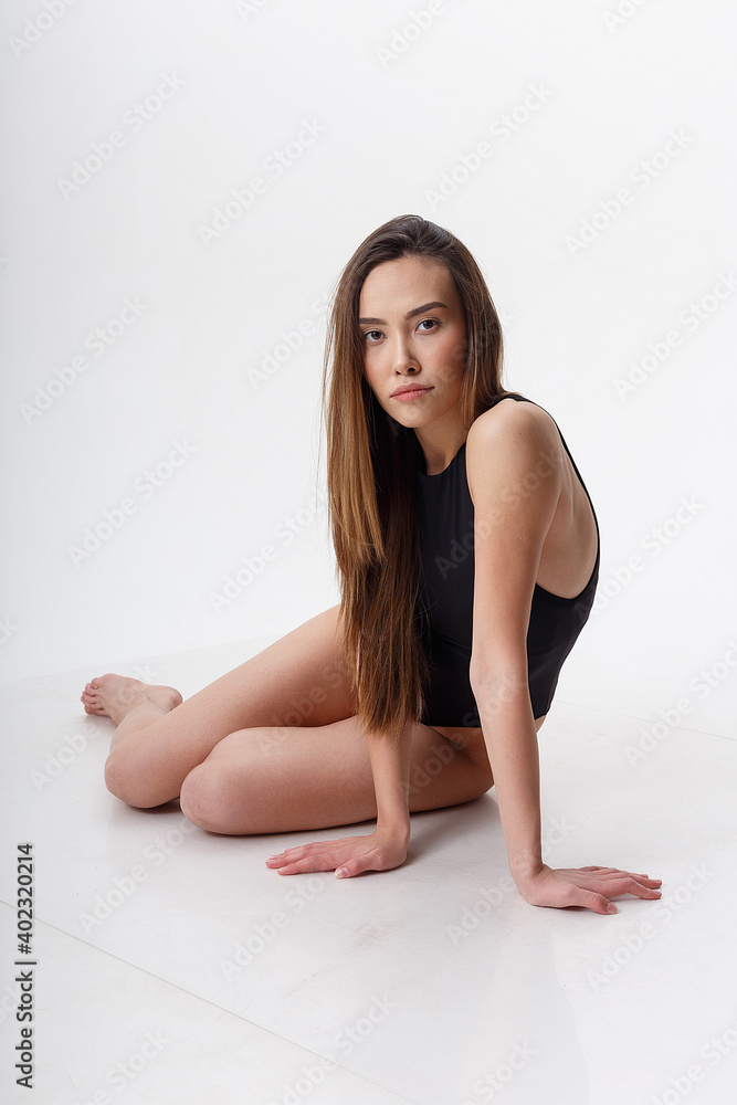 sexy asian woman with long hair posing in black lingerie on white studio background with bare feet. attractive female sitting on floor with her knees bent. model tests of skinny lady in bodysuit sexy asian woman with long hair posing in black lingerie on white studio background with bare feet. attractive female sitting on floor with her knees bent. model tests of skinny lady in bodysuit