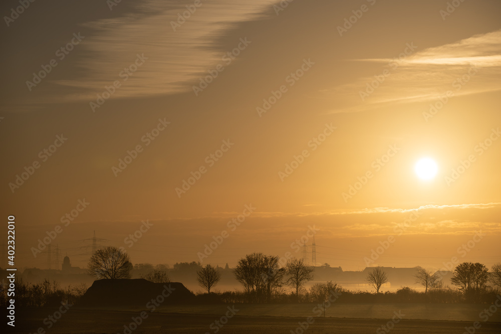 Sonnenaufgang über Feld und Dorf im Herbst/Winter mit Dunst Sonnenaufgang über Feld und Dorf im Herbst/Winter mit Dunst
