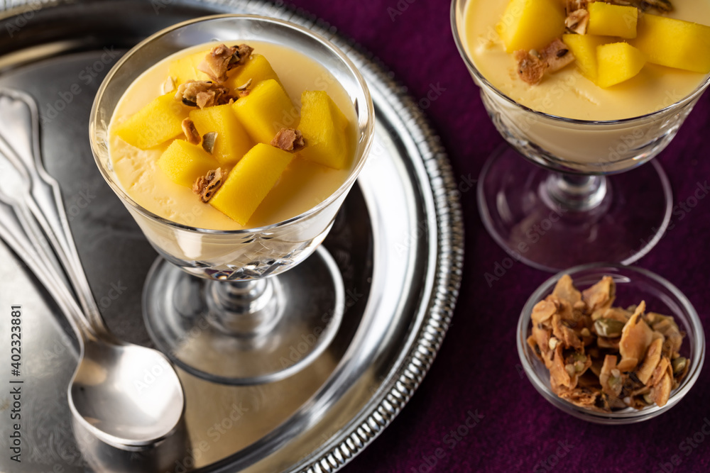 Close up of mango mousse dessert parfaits topped with granola ready for eating. Close up of mango mousse dessert parfaits topped with granola ready for eating.