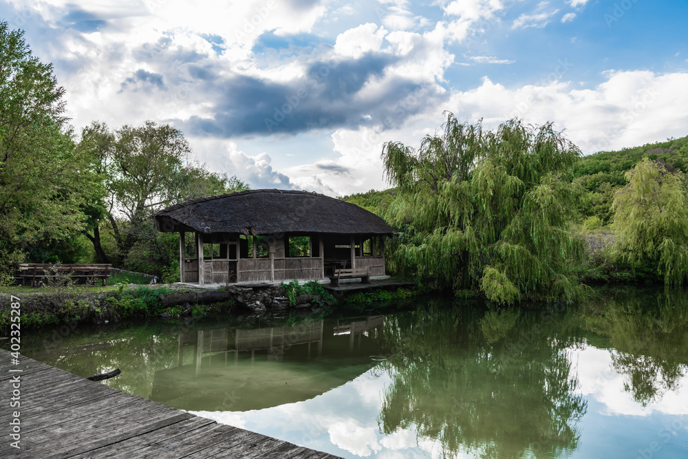 Obraz premium Wooden hut on the shore of the pond
