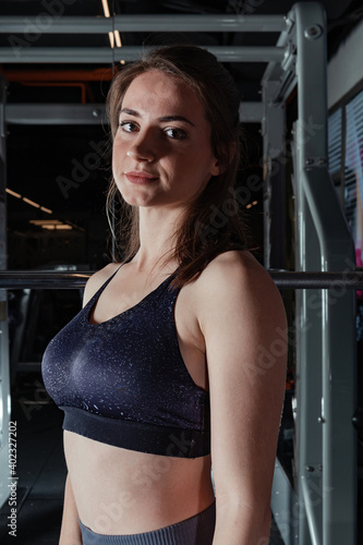 Beautiful young fitness woman doing squats with a barbell on the Smith Machine in the gym. Beautiful woman poses for the camera. © platinumArt