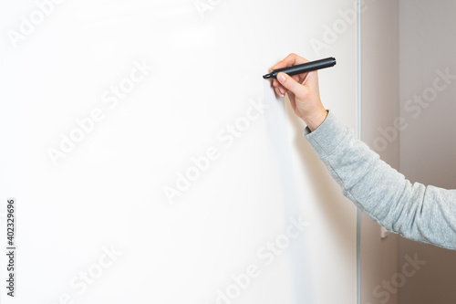 Office and business concept, hand-holding or writing with black marker on the whiteboard or backdrop. 