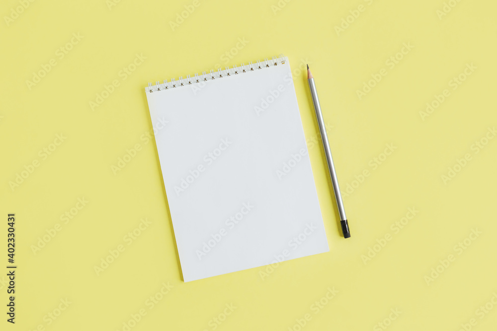 Notebook with blank page and pencil on a yellow background. Notebook with blank page and pencil on a yellow background.