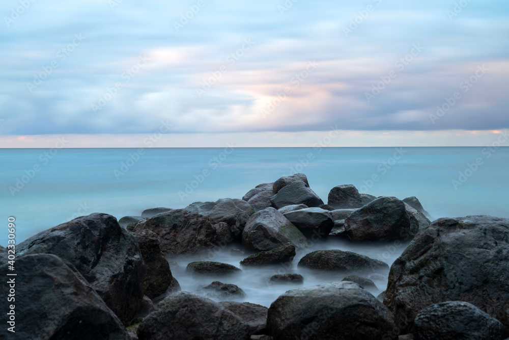 Boulders in ocean with cloudy sunset Boulders in ocean with cloudy sunset