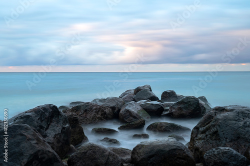 Boulders in ocean with cloudy sunset