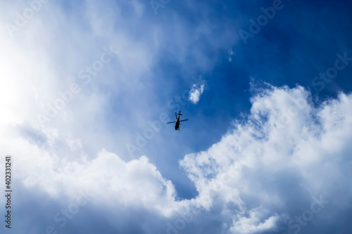 Blue sky with small helicopter flying into a thundercloud.